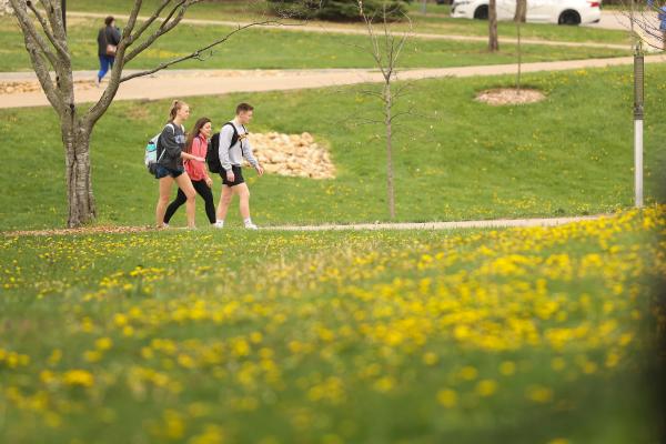 Students walk on campus with flowers blooming 
