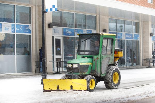 A snowplow pushing snow outside of The 90 on UK's campus.