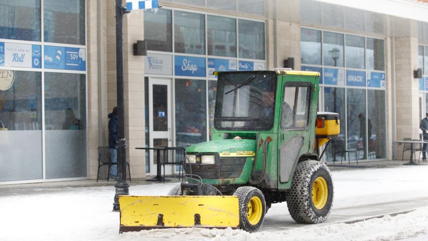 A snowplow pushing snow outside of The 90 on UK's campus.