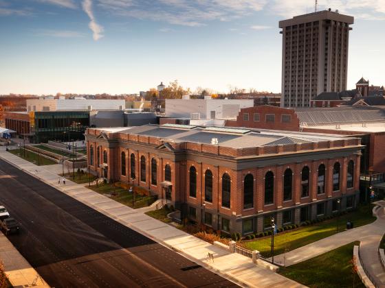 an aerial view of the Alumni Gym at sunset with some feathery clouds in the blue sky and the Patterson Office Tower rising in the background