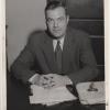 President Frank Dickey seated at his desk with his hands folded